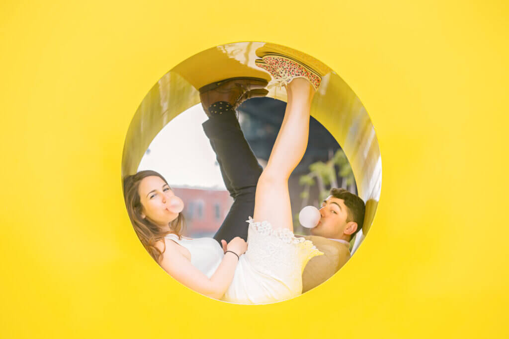 Creative NYC engagement photo in DUMBO, Brooklyn, with a couple using unique props to to create a save-the-date card.