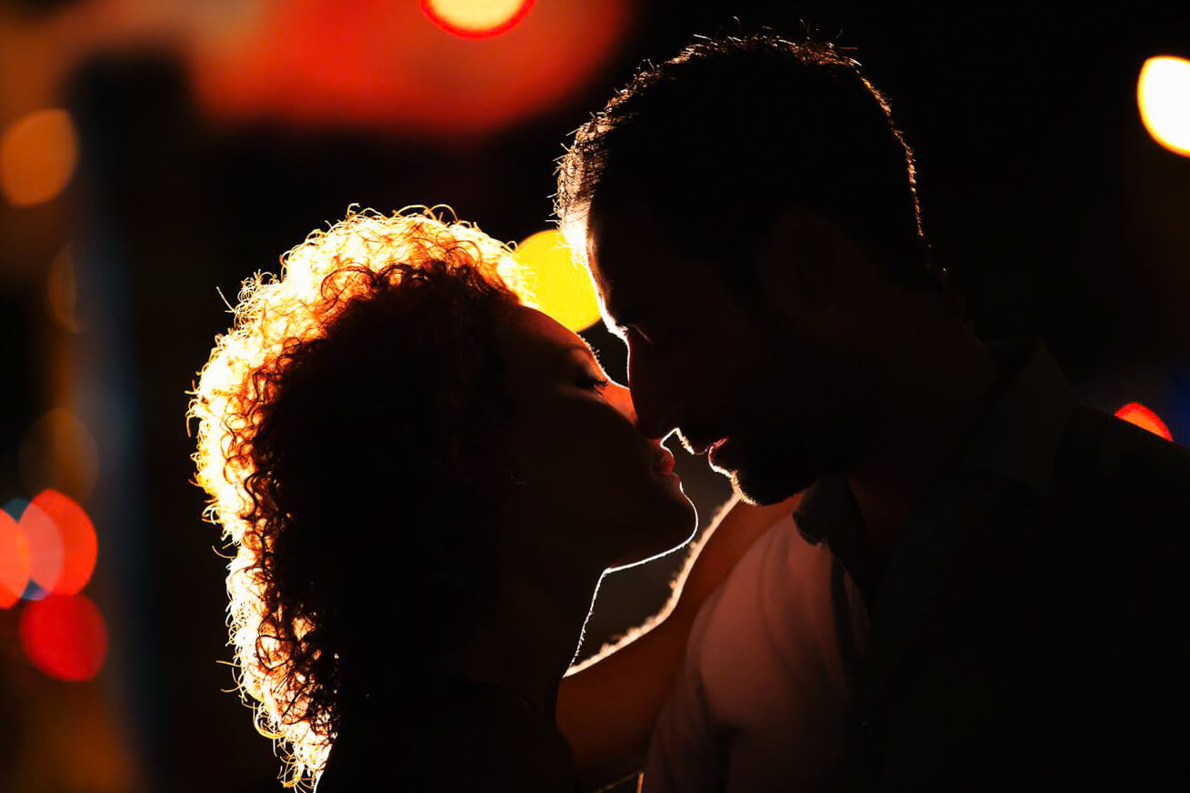 Couple passionately kissing amidst the dazzling lights of Times Square during their nighttime NYC engagement photo session.